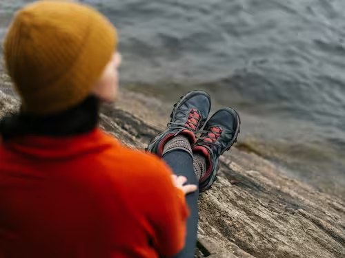 A person in an orange coat sitting by the water